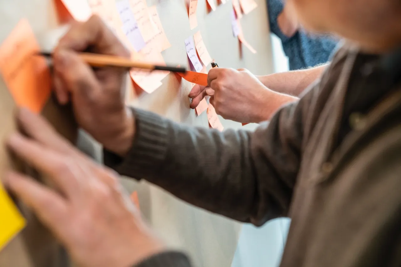 Teilnehmer arbeiten mit Sticky Notes am EventStorming-Board